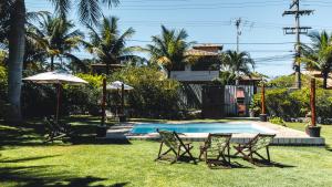 um quintal com uma piscina e duas cadeiras e um guarda-sol em Bacana Hotel Boutique em Búzios