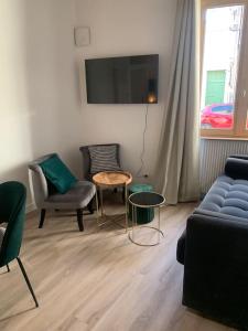 uma sala de estar com um sofá, cadeiras e uma mesa em Appartement velouté em Dijon