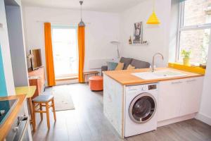 a kitchen and living room with a washing machine at Chequer - seafront 1 bed ground floor garden flat in Cleethorpes