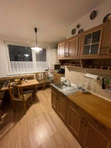 a kitchen with wooden cabinets and a table and a dining room at Apartmán DoMa - Tatranská Lomnica in Tatranská Lomnica
