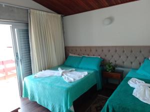 - une chambre avec 2 lits avec des draps verts dans l'établissement Hospedagem Virginia Bracelli, à Campos do Jordão