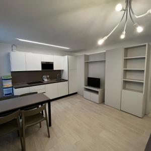a kitchen with white cabinets and a dining table at Smart Apartments Palazzo Mazzini in Rovereto