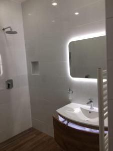 Baño blanco con lavabo y espejo en Hajnal Vendégház, en Kéked