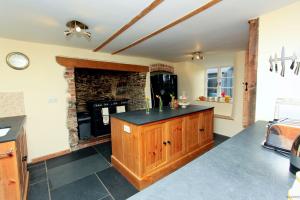 a kitchen with a stone fireplace in a room at Poyers Farmhouse in Wrafton