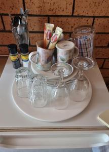 a tray with glasses and cups on a table at La Cochon Rose Motel in Saint Arnaud