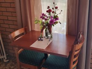 a wooden table with a vase of flowers on it at La Cochon Rose Motel in Saint Arnaud