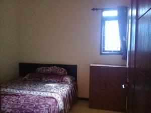 een kleine slaapkamer met een bed en een raam bij Azalea Homestay in Batu +3 foto's