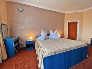 Un dormitorio con una cama azul con almohadas. en Hotel Belvedere en Piatra Neamţ