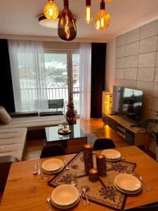 een woonkamer met een houten tafel met stoelen en een televisie bij Górski Apartament Olimpijska 1L in Szczyrk
