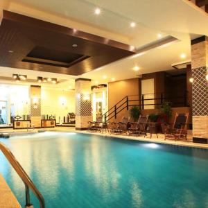a large swimming pool in a hotel with tables and chairs at KTK Pattaya Hotel & Residence in Pattaya Central