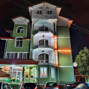 a tall building with cars parked in front of it at Hotel Belvedere in Piatra Neamţ