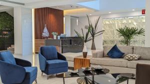 a living room with blue chairs and a couch at Hotel Fray Select in Tepic