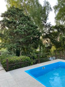 una piscina azul con una valla y árboles en MEIN HAUS en Sierra de los Padres