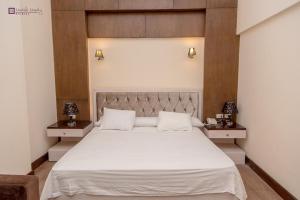 a bedroom with a large white bed with two night stands at Ultra Loaloa Nile Maadi Hotel in Cairo