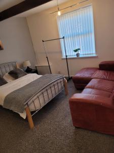 a bedroom with a bed and a couch and a window at No 2 Decent Home -Large Deluxe bedroom in Dukinfield
