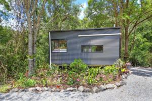 ein kleines schwarzes winziges Haus im Wald in der Unterkunft Holiday with Nature in Cooran