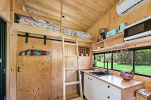 eine Küche in einem winzigen Haus mit Holzwänden in der Unterkunft Holiday with Nature in Cooran