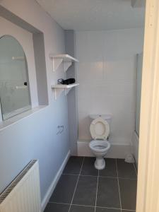 La salle de bains blanche est pourvue de toilettes et d'un miroir. dans l'établissement No 2 Decent Home -Large Deluxe bedroom, à Dukinfield