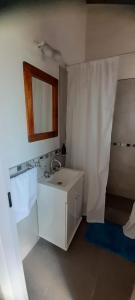 Baño blanco con lavabo y espejo en Magnolia's Cabañas en Tandil