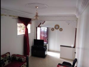 een woonkamer met een bank en een televisie bij Appartement meublé près du grand souk Elhad in Agadir