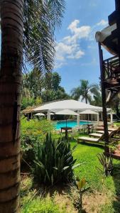 a resort with a pool and a large umbrella at Hotel Los Pinares in San Pedro +59 photos