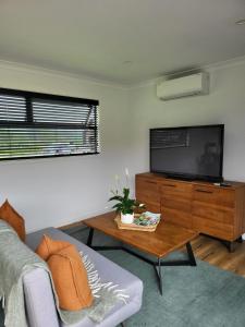 a living room with a couch and a flat screen tv at Kotuku Cottage in Tauranga