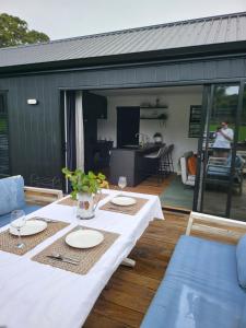 a table with plates on it on a patio at Kotuku Cottage in Tauranga