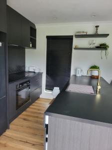 uma cozinha com um balcão preto e um lavatório em Kotuku Cottage em Tauranga