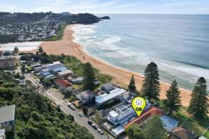 una vista aérea de una playa con una señal de velocidad amarilla en Bahia by the Beach, en Avoca Beach