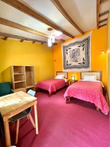 two beds in a room with yellow walls at Pisac Inca Guest House in Pisac