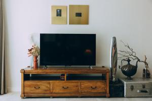 telewizor z płaskim ekranem siedzący na szczycie drewnianego centrum rozrywki w obiekcie ‘The Lumos’ Designer home Close to Olympic Park w mieście Sydney