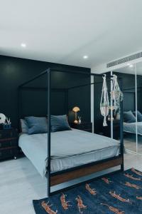 1 dormitorio con cama con dosel y pared negra en ‘The Lumos’ Designer home Close to Olympic Park, en Sídney