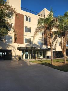 an office building with a palm tree in front of it at Departamento Ribera in Ramallo