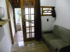 a living room with a couch and an open door at ICE POINT SURF HOUSES Praia do Rosa- Necessário Pré-pagamento Metade Valor Total in Praia do Rosa