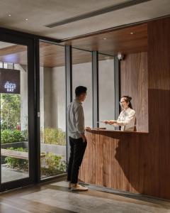 胡志明市的住宿－Triple E Hotel Metro Ben Thanh，站在柜台上的男女