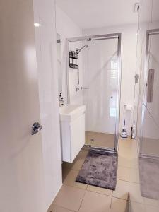 a white bathroom with a shower and a sink at Shared Bright and Cozy Room in Parramatta CBD - close to everything in Sydney