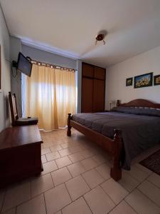 Un dormitorio con una cama y una silla y un televisor. en Mirador, en Las Grutas