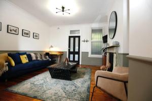 un soggiorno con divano blu e sedia di The Pavilion End - Central Paddington Apartment a Sydney