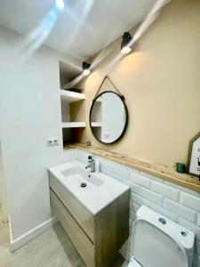 a bathroom with a sink and a mirror and a toilet at Cozy Apartment Near Sagrada Familia in Barcelona