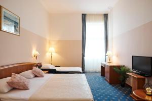 a hotel room with two beds and a flat screen tv at Hotel Lovran in Lovran