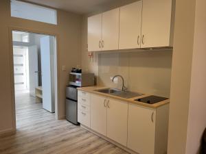a kitchen with white cabinets and a sink and a microwave at The Runaway in Dargaville