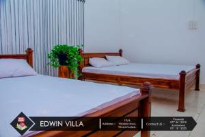 two beds in a room with avertisement for at Edwin Villa in Trincomalee