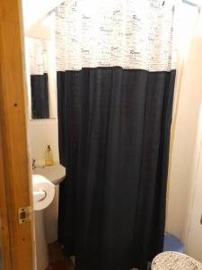 a bathroom with a black shower curtain and a sink at Agradable Cabaña campestre a 7 minutos de Osorno in Osorno
