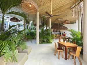 ein Restaurant mit einem Tisch, Stühlen und Palmen in der Unterkunft Beautiful Swim-Up Apartment with Private Terrace & Hammoc, Pool & Gym in Tulum