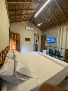 1 cama blanca grande en una habitación con sillas en Suítes Naldiane, en Imbassai