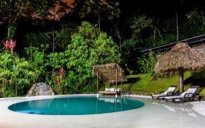 a swimming pool with two chairs and a umbrella at Kuyana Amazon Lodge in Archidona