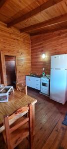 una cocina con nevera y una mesa en una cabaña en Cabañas Tres Pinos en Sierra de la Ventana