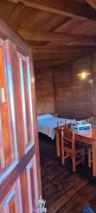 una habitación con una mesa y una cama en una cabaña en Cabañas Tres Pinos en Sierra de la Ventana
