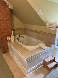 a large bath tub in a bathroom with a brick wall at The Red Coat in Niagara on the Lake