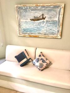 a white couch with pillows and a painting on the wall at Linda casa em Geribá in Búzios